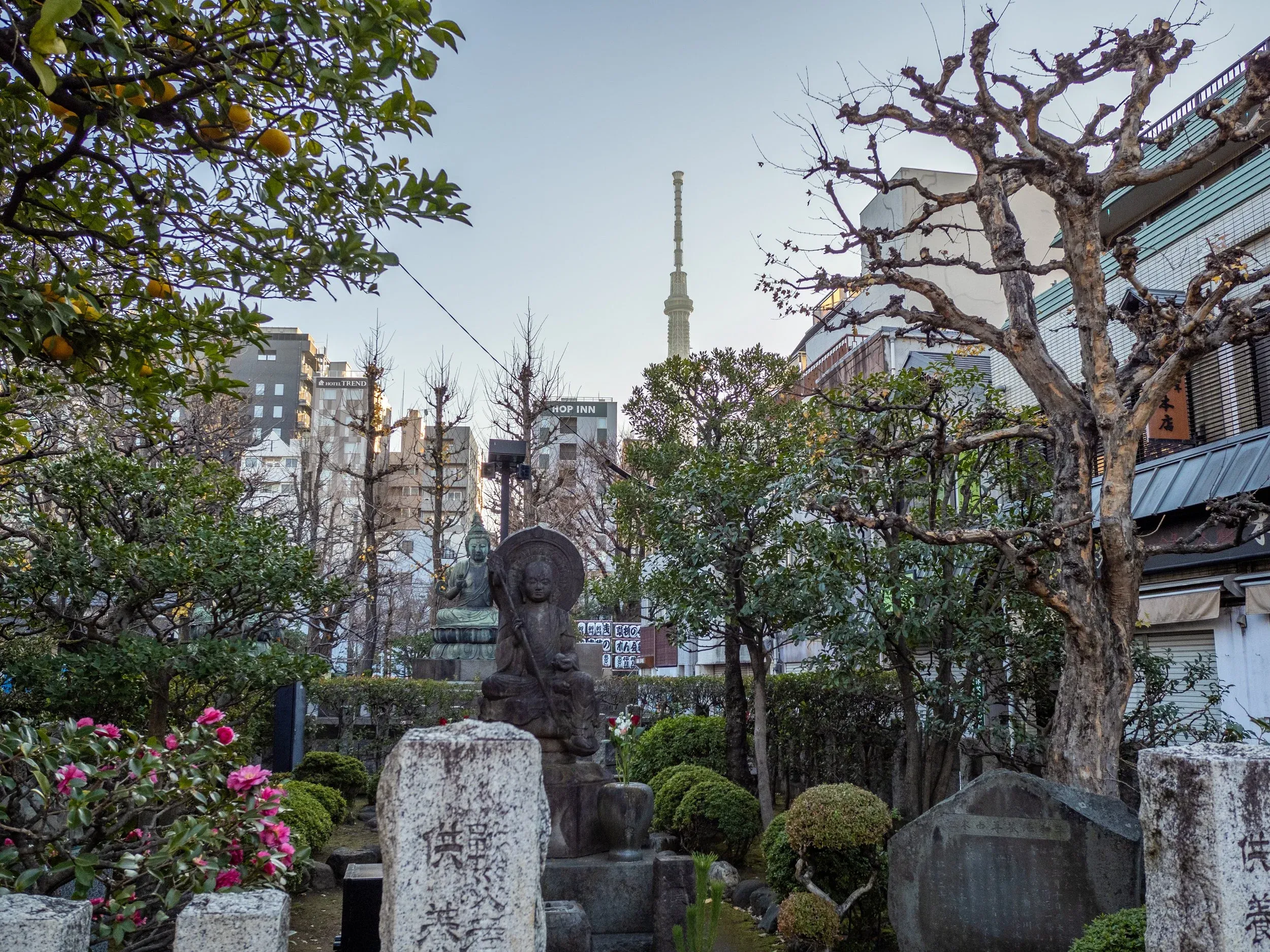 Older Buddhist statues with the imposing Tokyo Skytree in the background